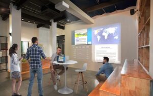 Epson EBL730u projector in an open meeting space, displaying a bright and detailed presentation on a large screen