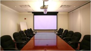 Grandview CNV Series motorized screen in a compact boardroom setup with a modern projector.